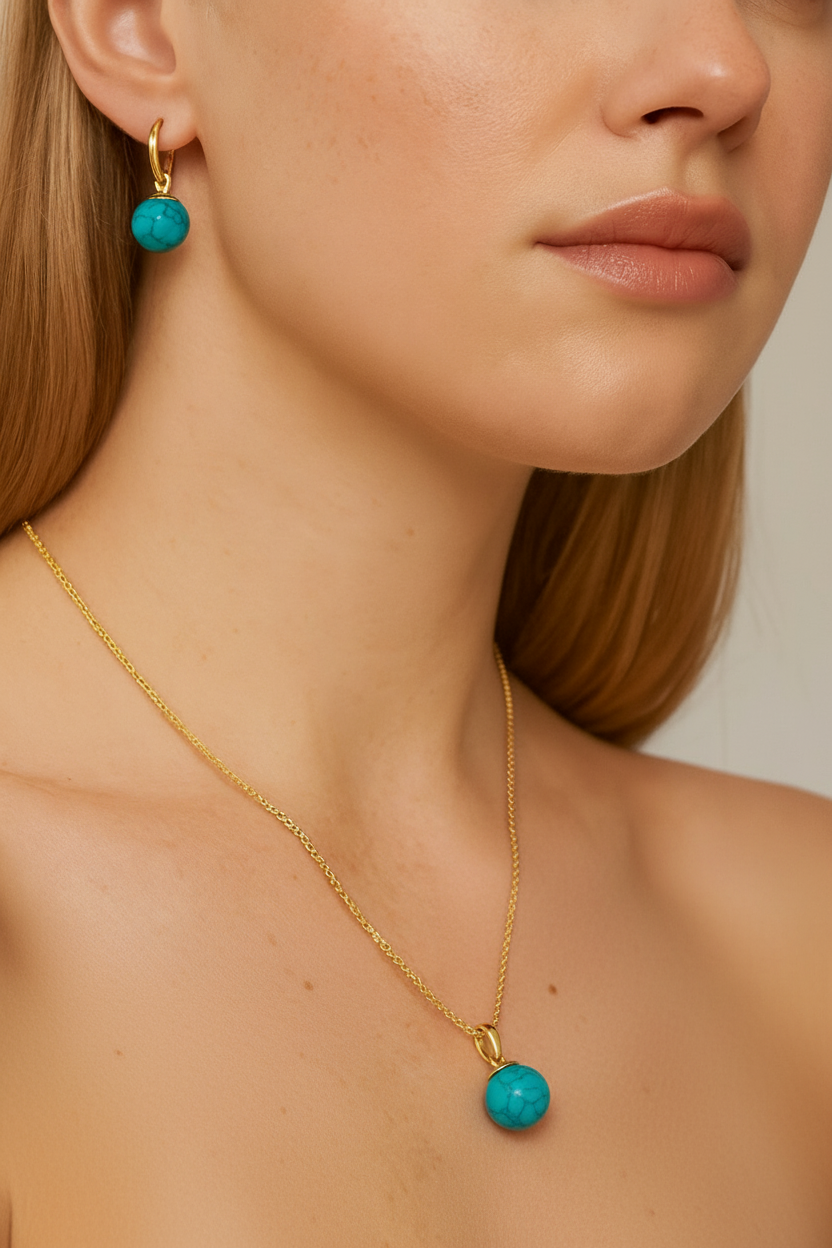 Close-up of a woman wearing gold jewelry with turquoise stones, including earrings and a necklace.