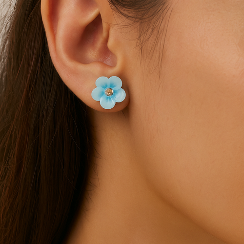 Close-up of an ear wearing a blue flower-shaped earring.