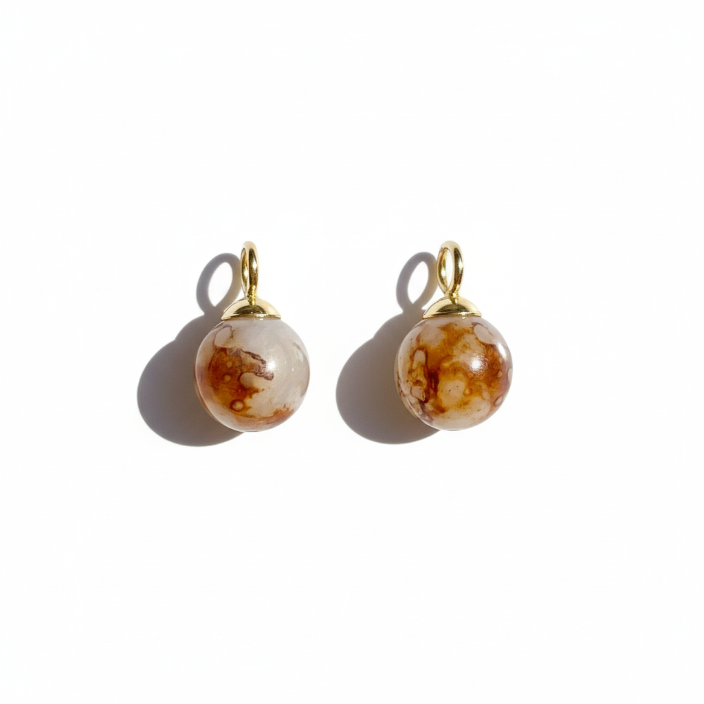 Pair of earrings with marbled brown and beige beads on a white background