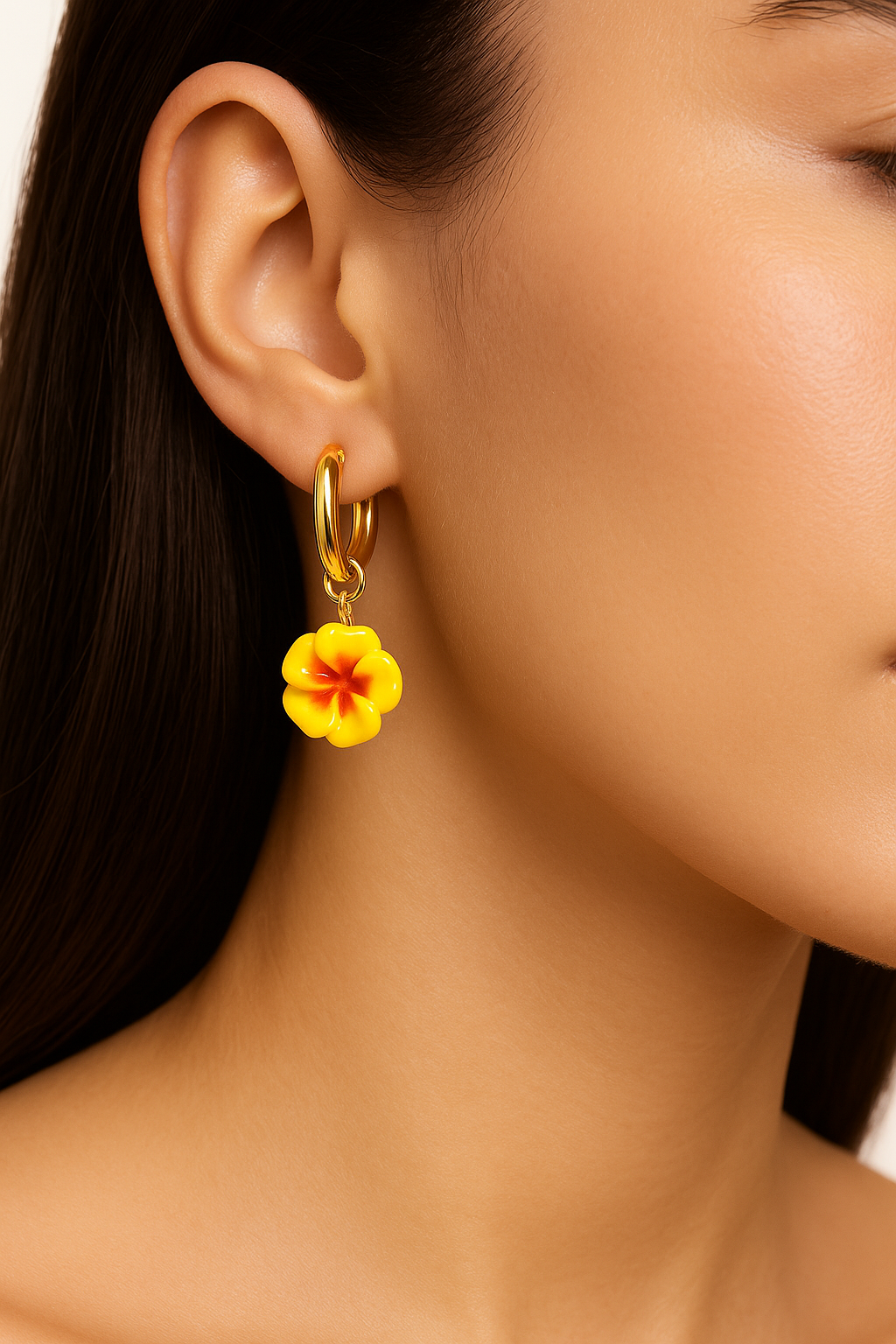 Close-up of a woman wearing a golden hoops with detachable yellow floral charms