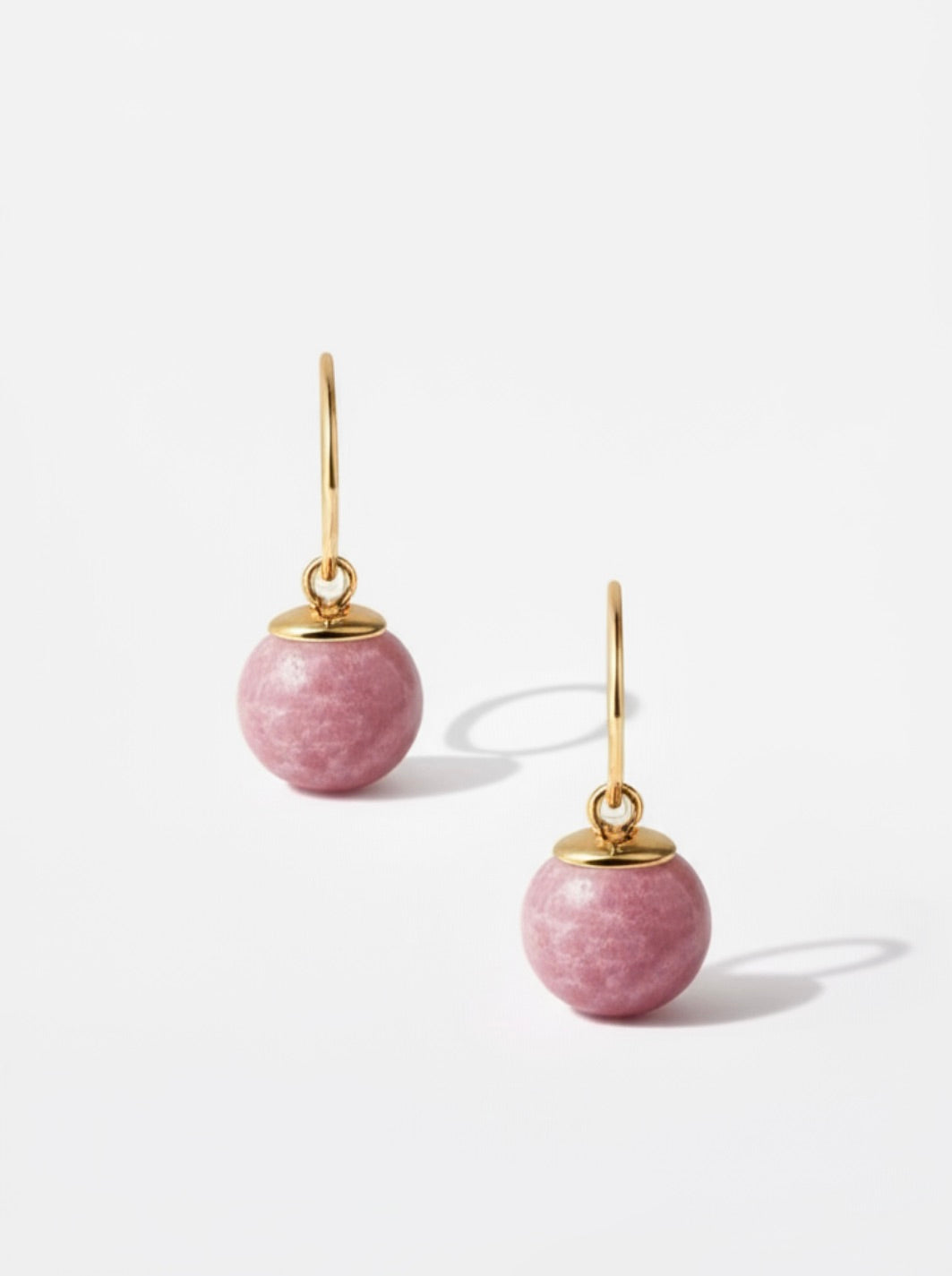 Pink earrings with gold hooks on a white background
