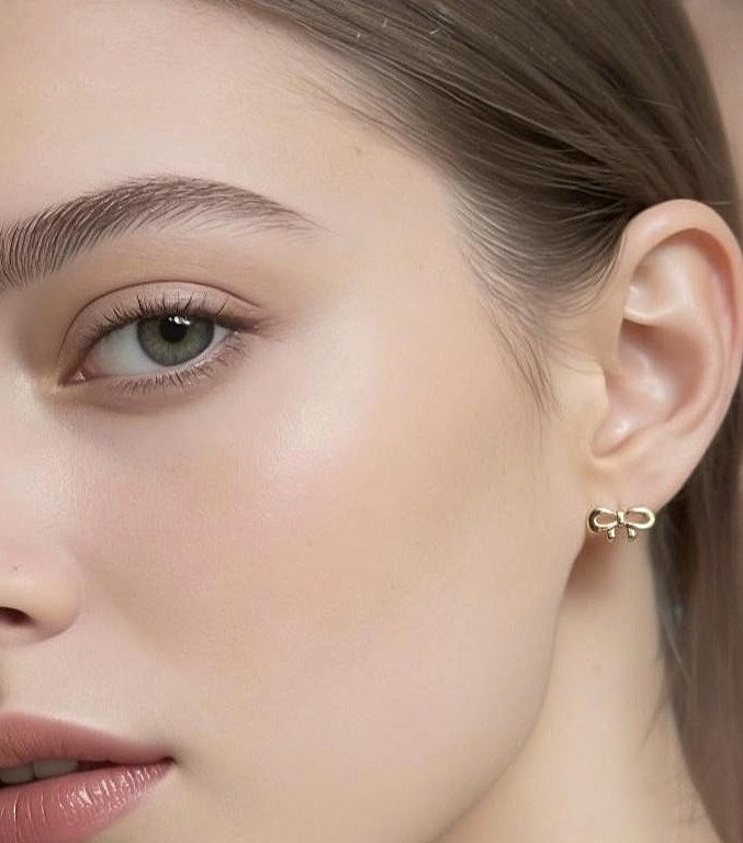 Close-up of a woman wearing gold bow-shaped earrings.