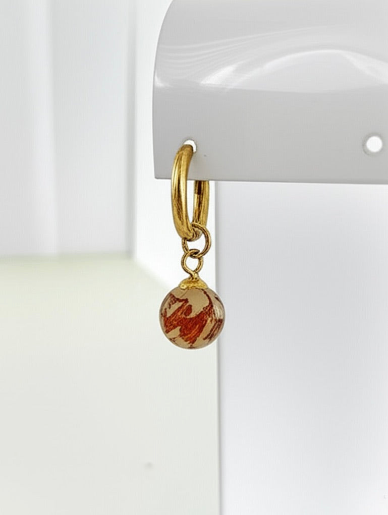 Gold hoop earring with a round brown drop charm on a white background