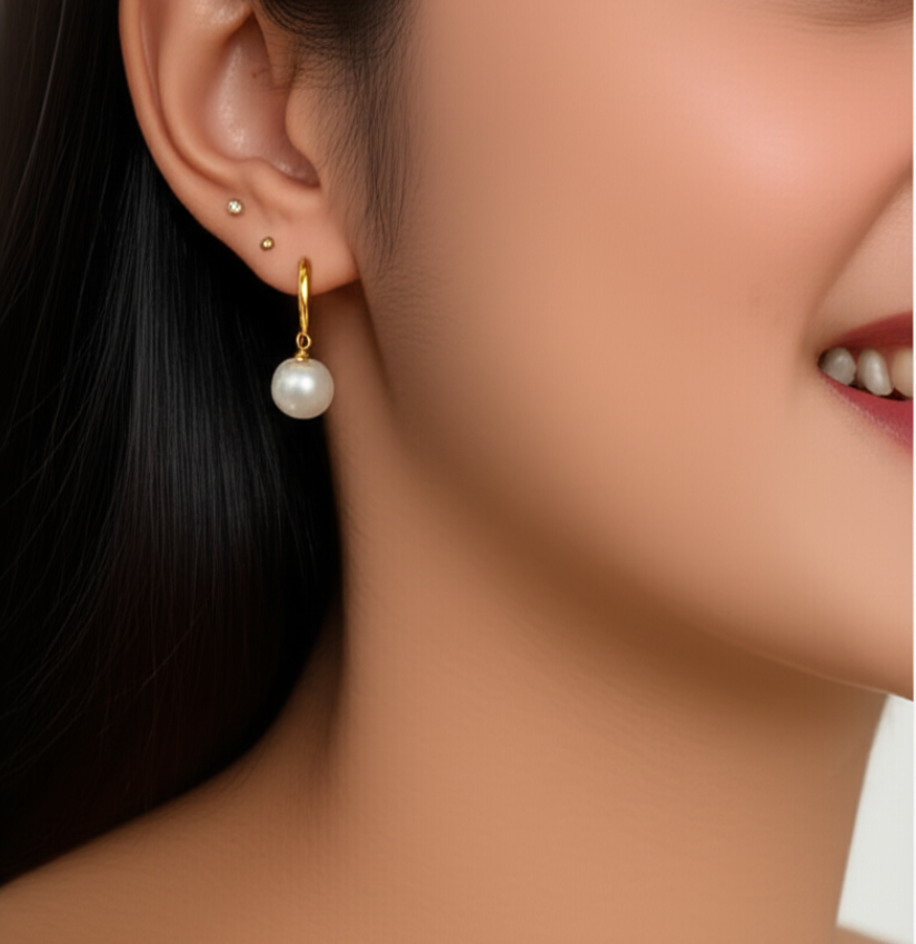 Pearl dangle charms on earrings worn by a model with a close-up of the ear and neck.