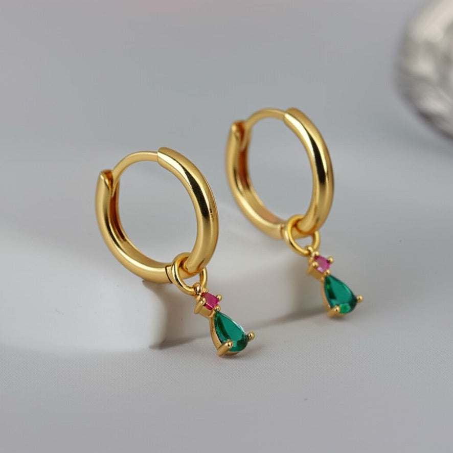 Gold hoop earrings with gemstone drops on a light gray background