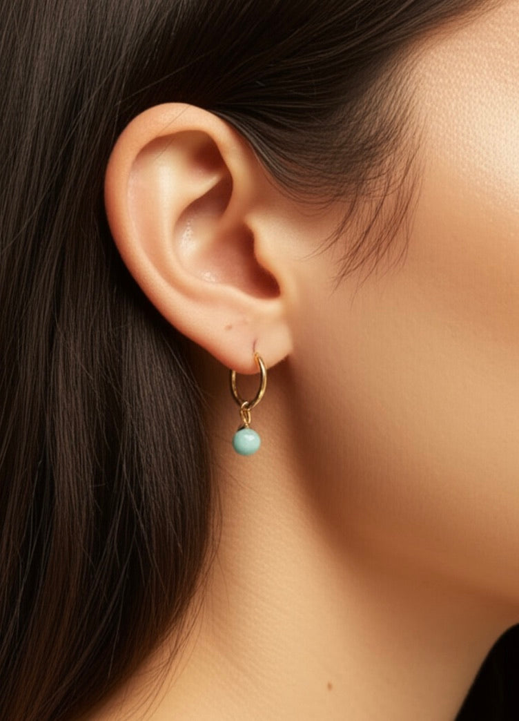 Close-up of an ear wearing a gold hoop earring with a nephrite bead.