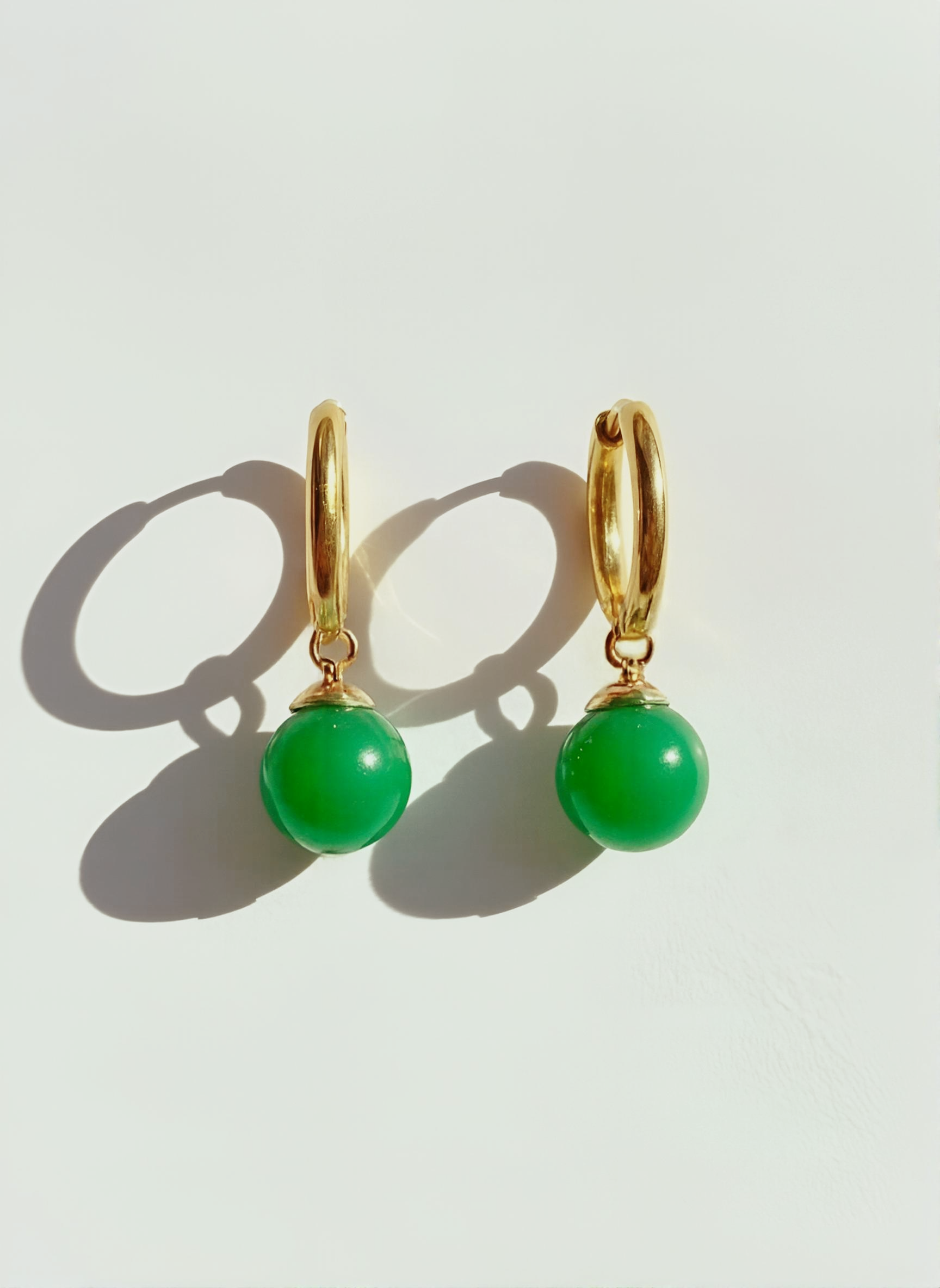 Gold hoop earrings with attached green bead dangles