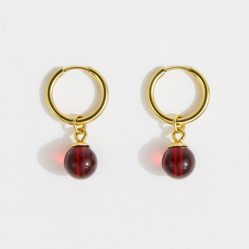 Gold hoop earrings with red beads on a white background