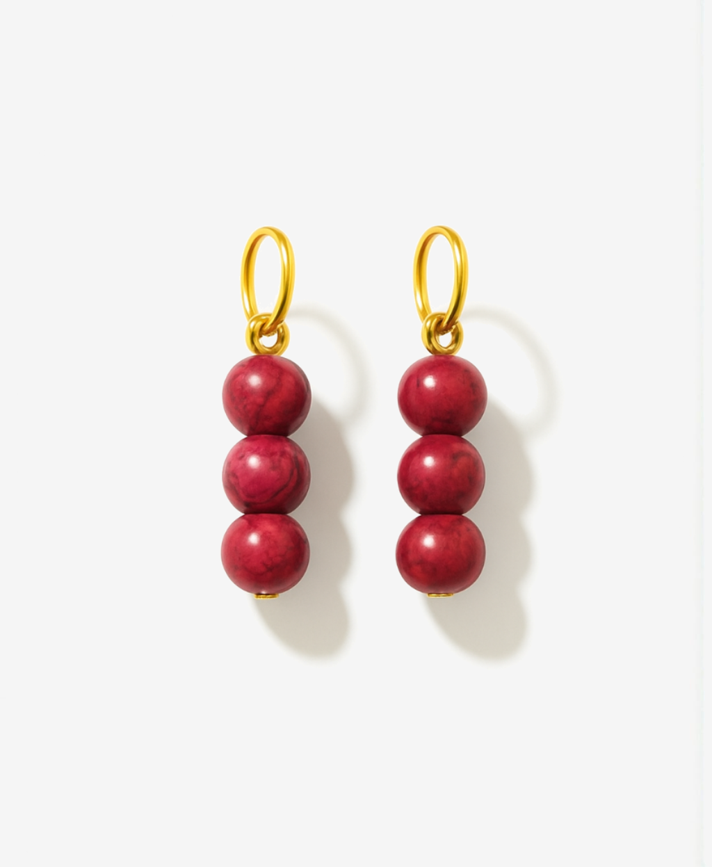 Pair of red beaded charms for earrings with gold hooks on a white background