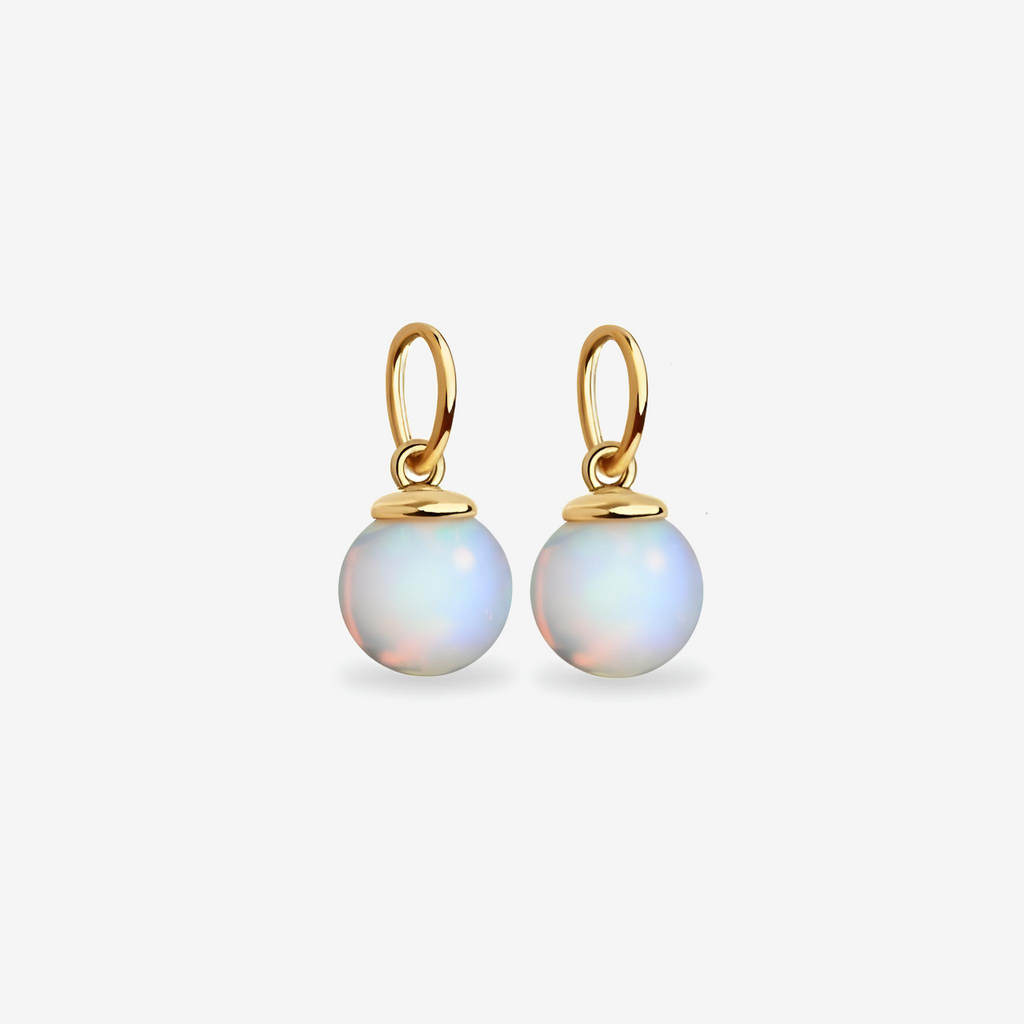 Gold earrings with round, light-colored gemstones on a white background