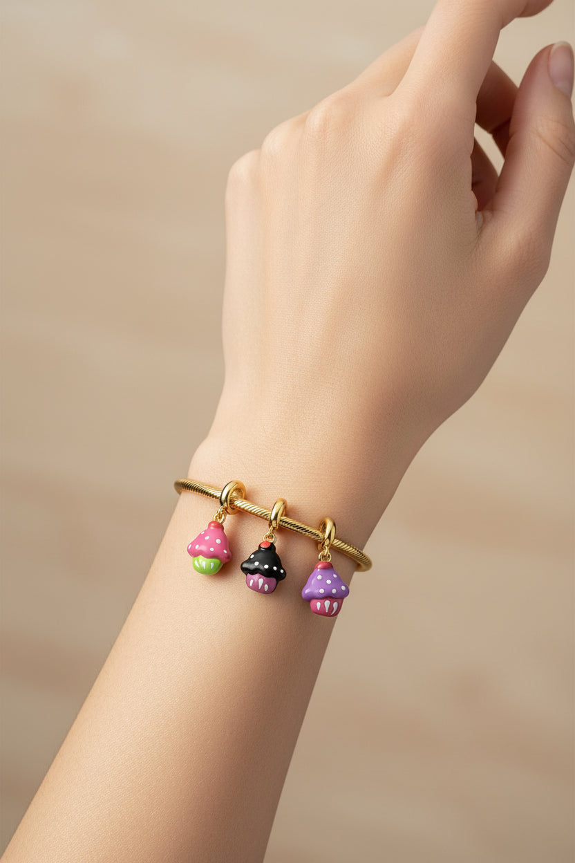 Hand wearing a gold bracelet with colorful cupcake charms 